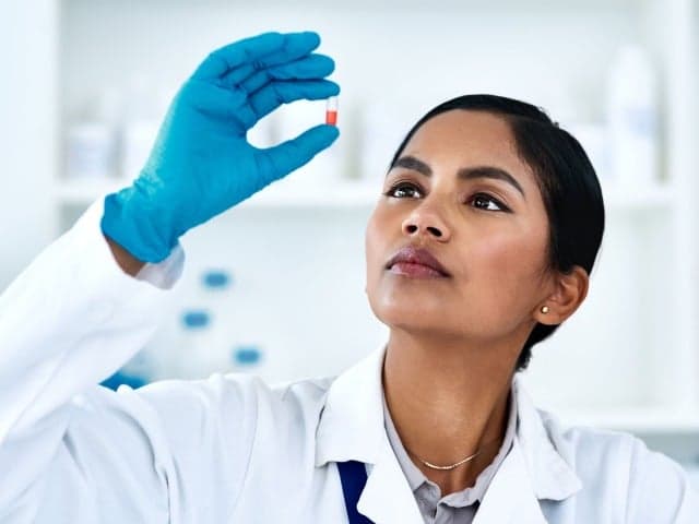 Element  scientist in white coat and safety goggles in life sciences testing laboratory interacting with advanced analytical equipment for pharmaceutical research