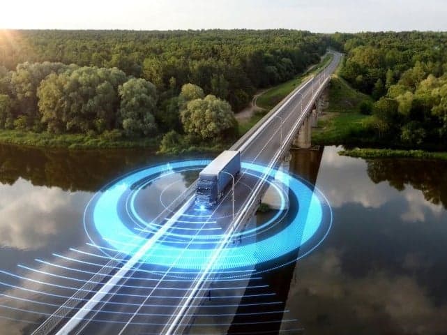 Semi truck driving on bridge surrounded by ring showing range of autonomous vehicle sensing technology