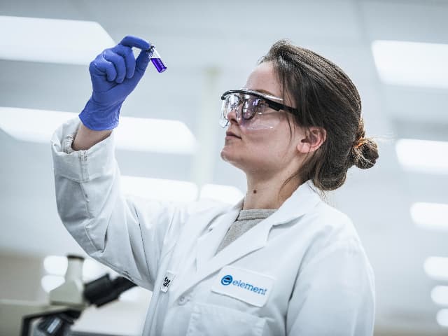 Element pharmaceutical testing scientist with laboratory equipment for drug development and compliance