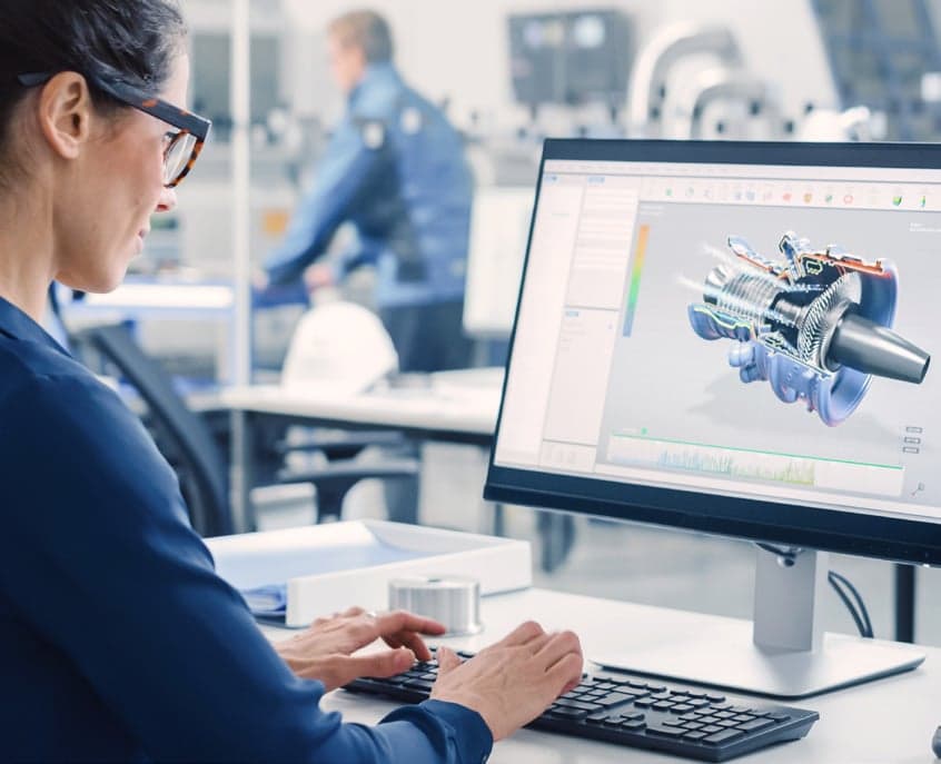 Testing engineer looking at a computer with an image of a cutaway of an engine from a digital simulation