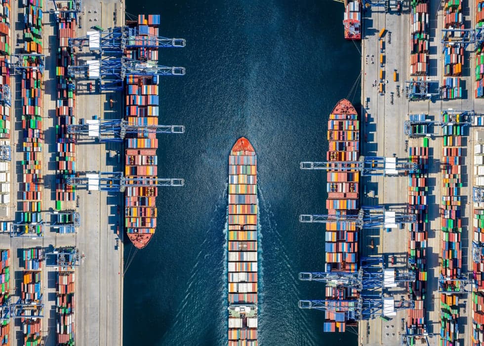 Aerial view of large cargo ships in a port laden with colorful shipping containers