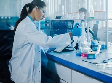 image of scientist in a lab putting liquid in a flask