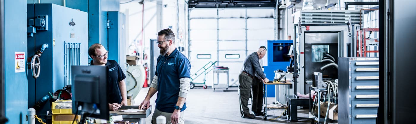 Two testing engineers chatting in Element product testing laboratory with environmental simulation testing chambers in background