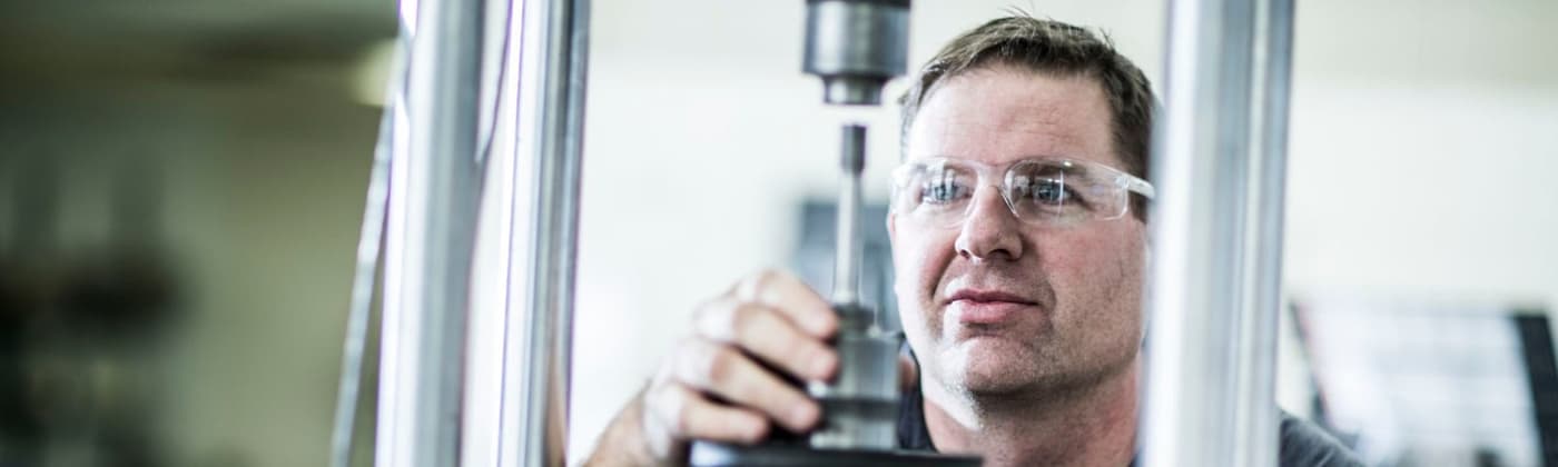 Testing engineer adjusting metal sample in mechanical testing frame