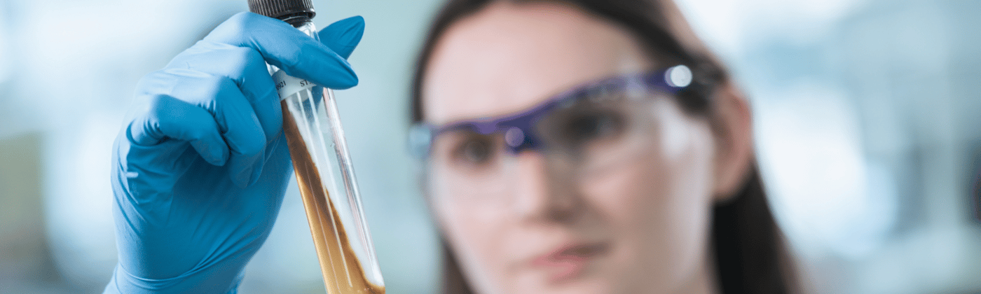 Scientist examining a sample vial for biologics analytical testing