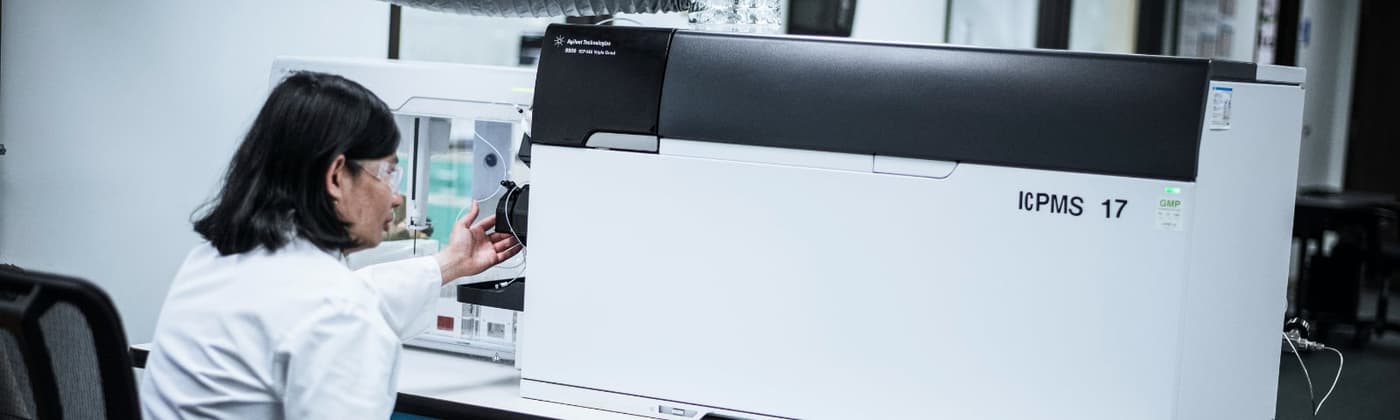 Scientist operating an ICP-MS instrument in a pharmaceutical testing laboratory