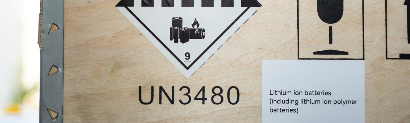 Wooden shipping crate labeled UN3480 for lithium ion batteries with hazardous materials warning symbols.