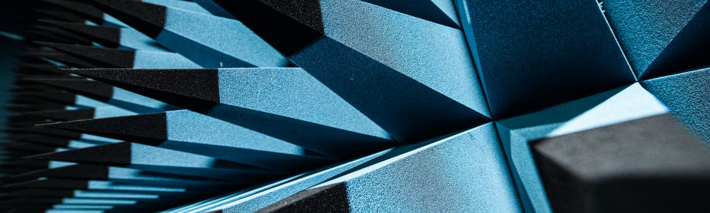 Close-up of blue pyramid-shaped RF-absorbing foam panels inside an anechoic chamber used for EMC testing.