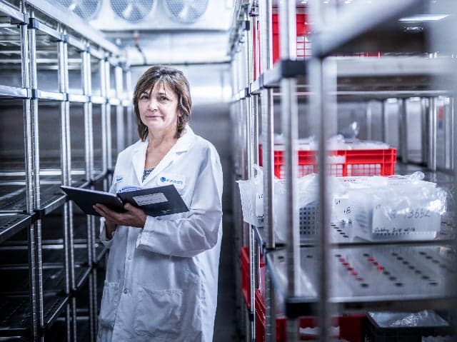 Pharmaceutical scientist reviewing stability program documentation in temperature-controlled storage facility