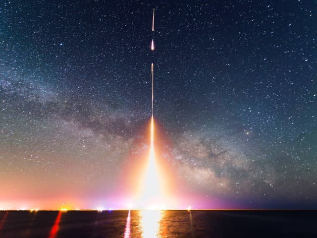 A rocket launching at night against a starry sky.