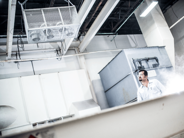 Test engineer watching as testing samples lowered into tank.