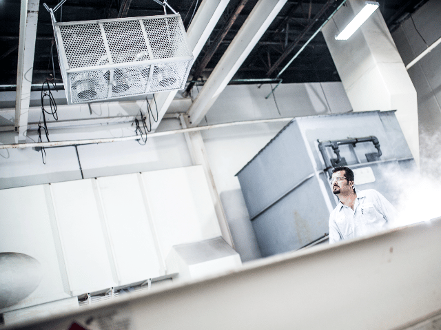 Test engineer watching as testing samples lowered into tank.