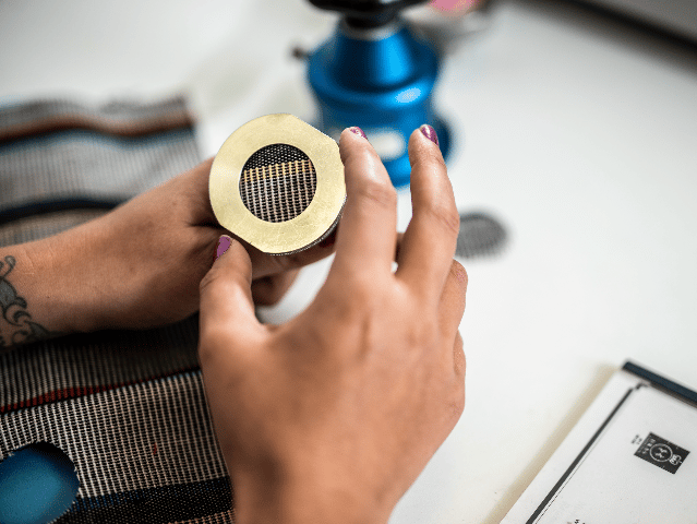 Hand holding a textile sample for testing at workbench.
