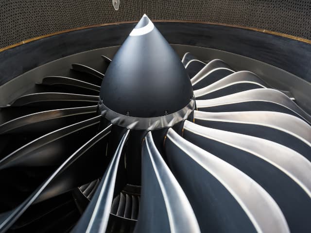 Close-up view of a commercial aircraft engine inlet featuring advanced composite fan blades with a sleek aerodynamic profile.