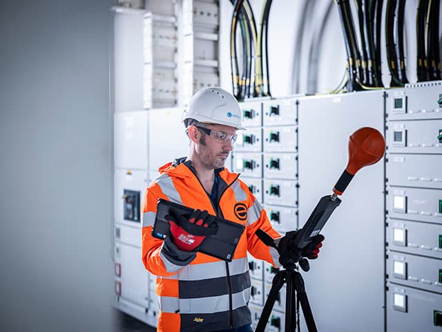 Technician conducting electromagnetic field survey with EMF meter in electrical facility