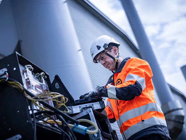 Technician operating flaring and biogas emissions monitoring equipment at an industrial facility