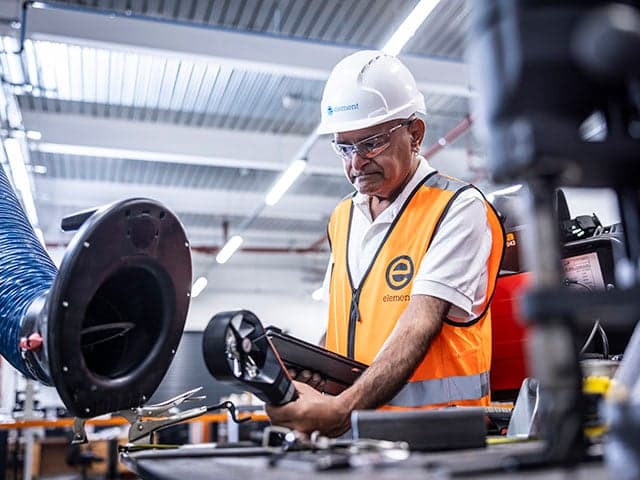 Technician monitoring welding fume exposure in industrial workshop