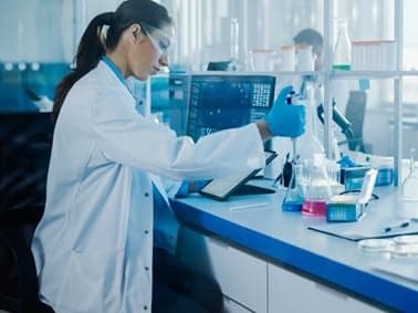 image of scientist in a lab putting liquid in a flask