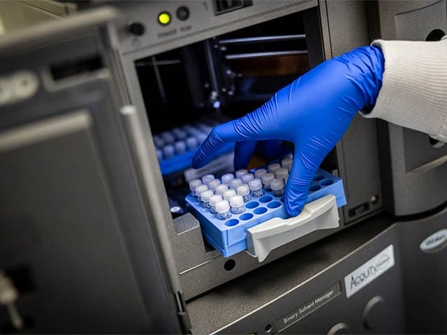 Chemist places pfas sample in instrument