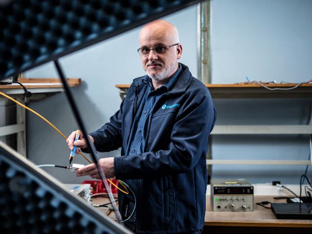 An Element engineer connecting cables to test equipment in a radio frequency testing laboratory.