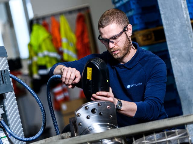 Element testing engineer operating specialized equipment for metal component analysis